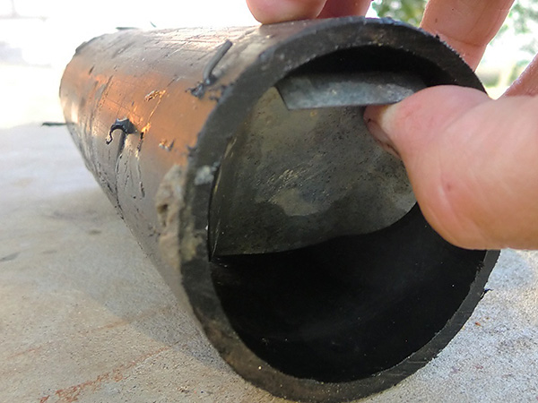 La photo montre un exemple de récupérateur de taupes fabriqué à la main à partir d'un morceau de tuyau en métal.